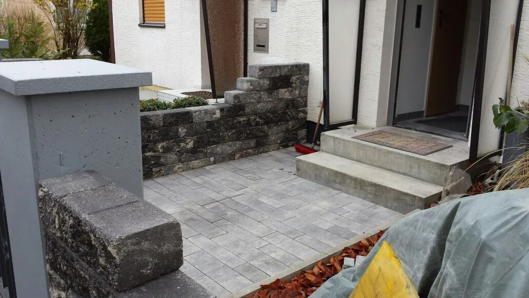 Gepflasterter Hauseingang mit Stufen und seitlichen Mauern